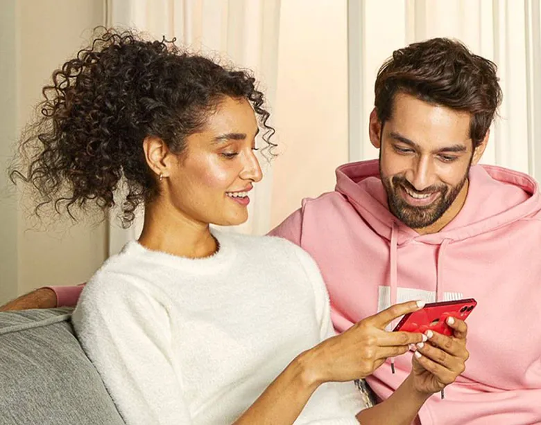A couple looking at a phone while sitting on a couch