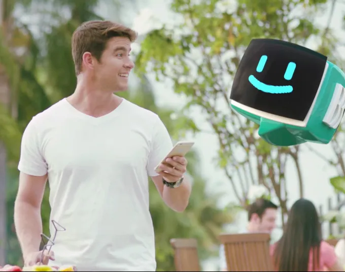 Seorang pria menatap kepala robot yang melayang dan tersenyum di sampingnya.