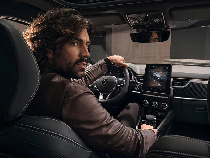 Um homem sentado no banco do motorista de um carro da Renault.