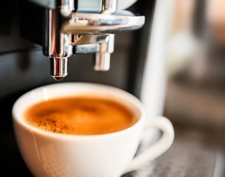 Mesin kopi mengeluarkan espresso yang baru diseduh ke dalam cangkir.