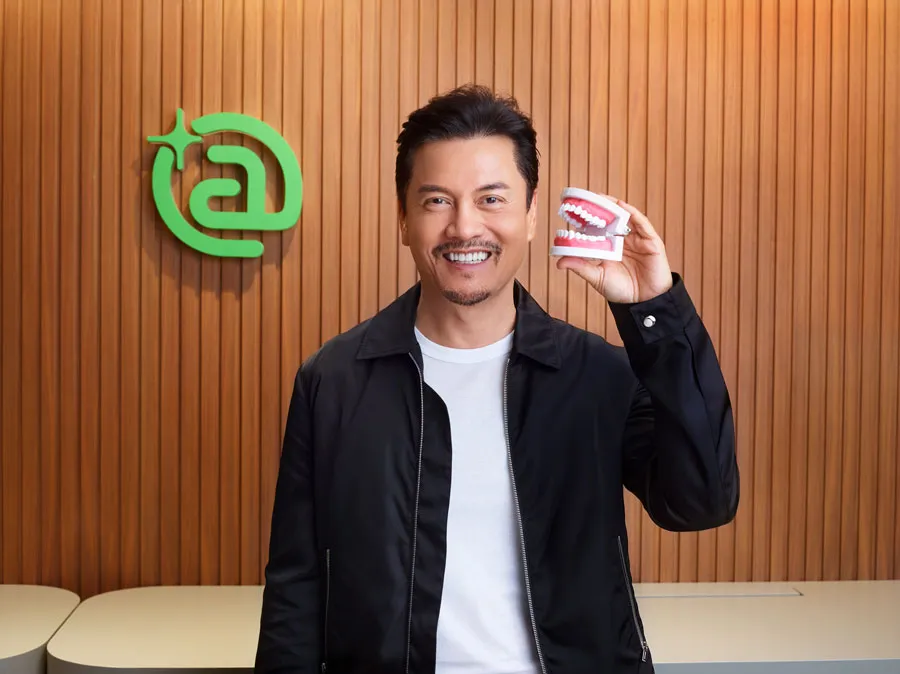A man is holding a dental prosthesis in his hand.