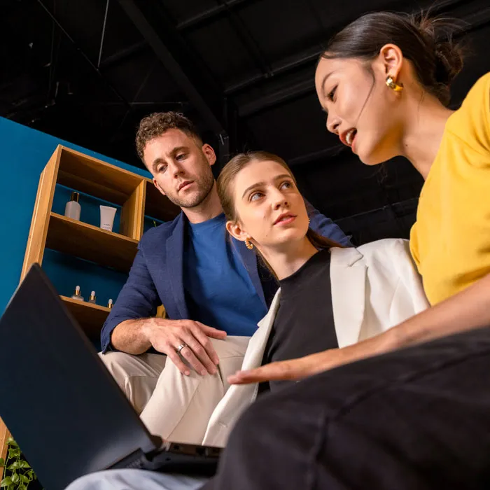 Un hombre y una mujer mirando a una mujer compartir la pantalla de su computadora portátil
