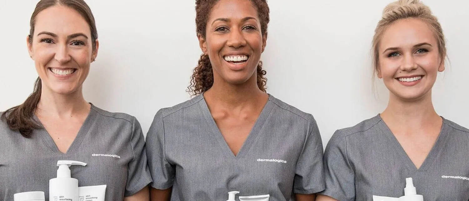 Trois dermatologues souriant et tenant des produits de soins pour la peau