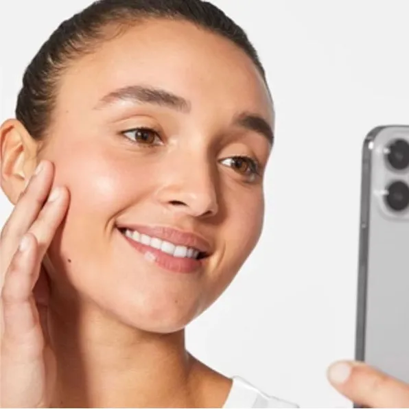 Mulher olhando para seu próprio reflexo no celular