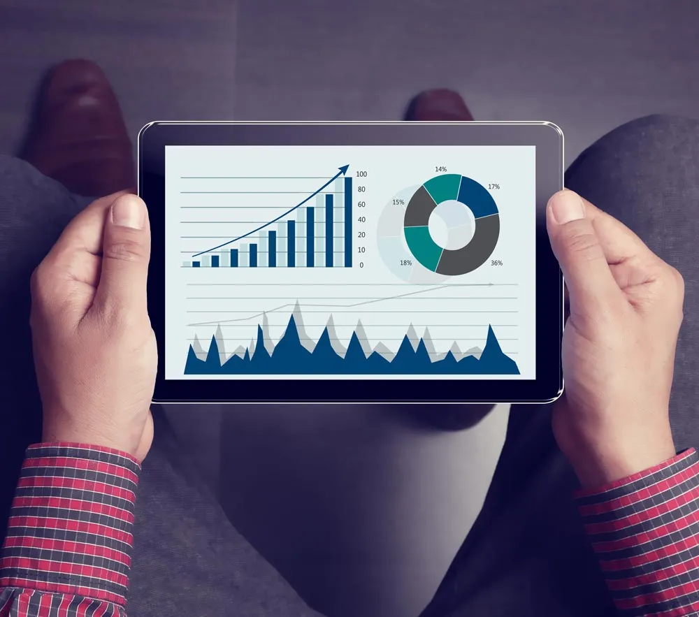 Un hombre sosteniendo una tableta y observando métricas y gráficos de marketing