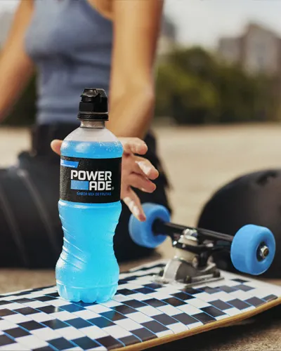 Una mujer toma su bebida Powerade que está encima de una tabla de skate.