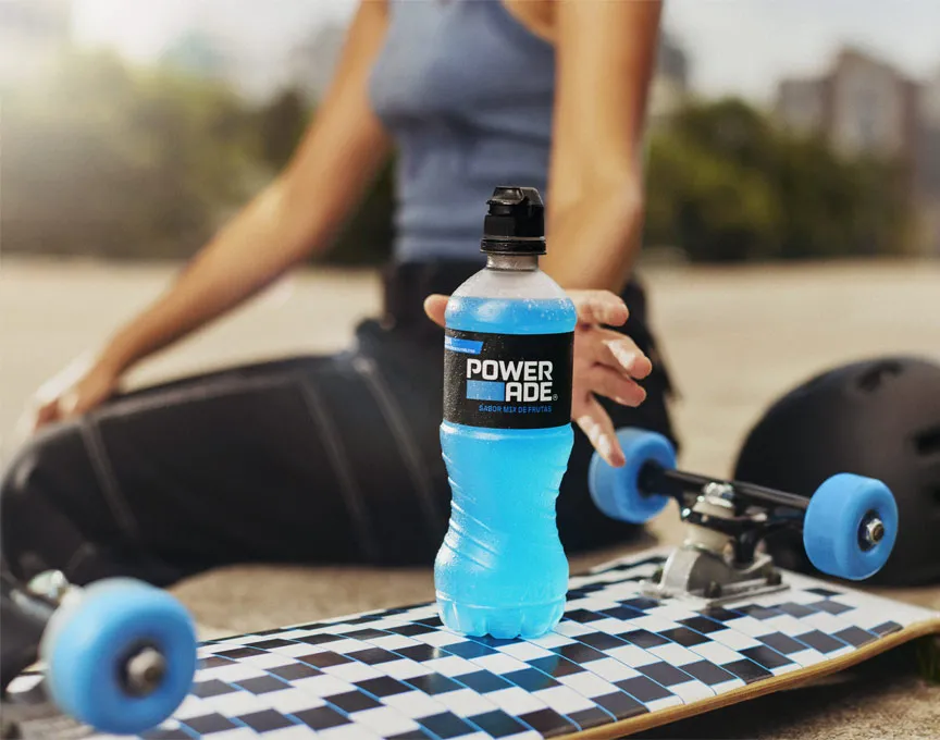 स्केटबोर्ड पर रखी Powerade ड्रिंक को थामने के लिए, हाथ बढ़ाती हुई एक महिला